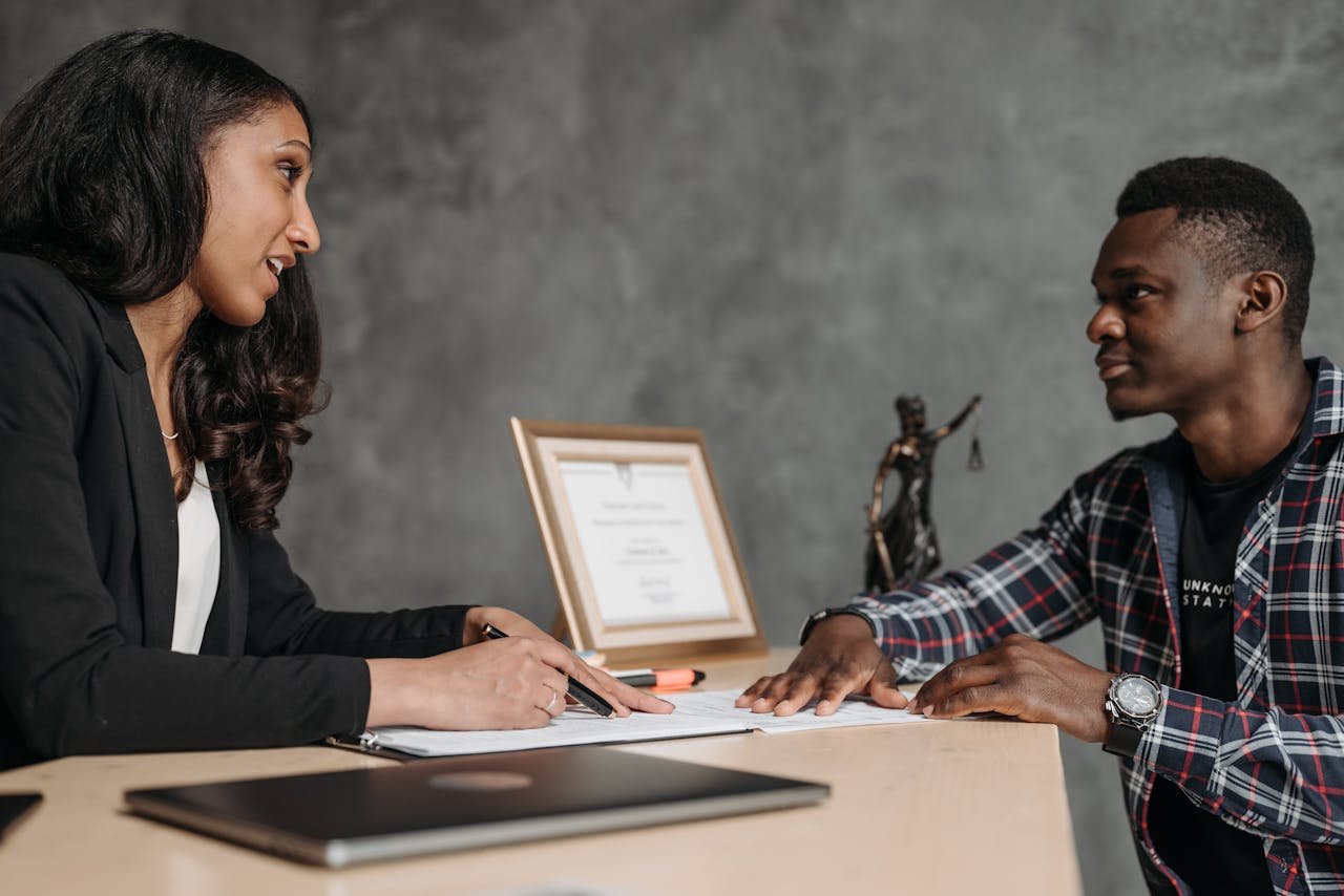 Two adults engaging in a professional conversation at an office desk, showcasing collaboration.